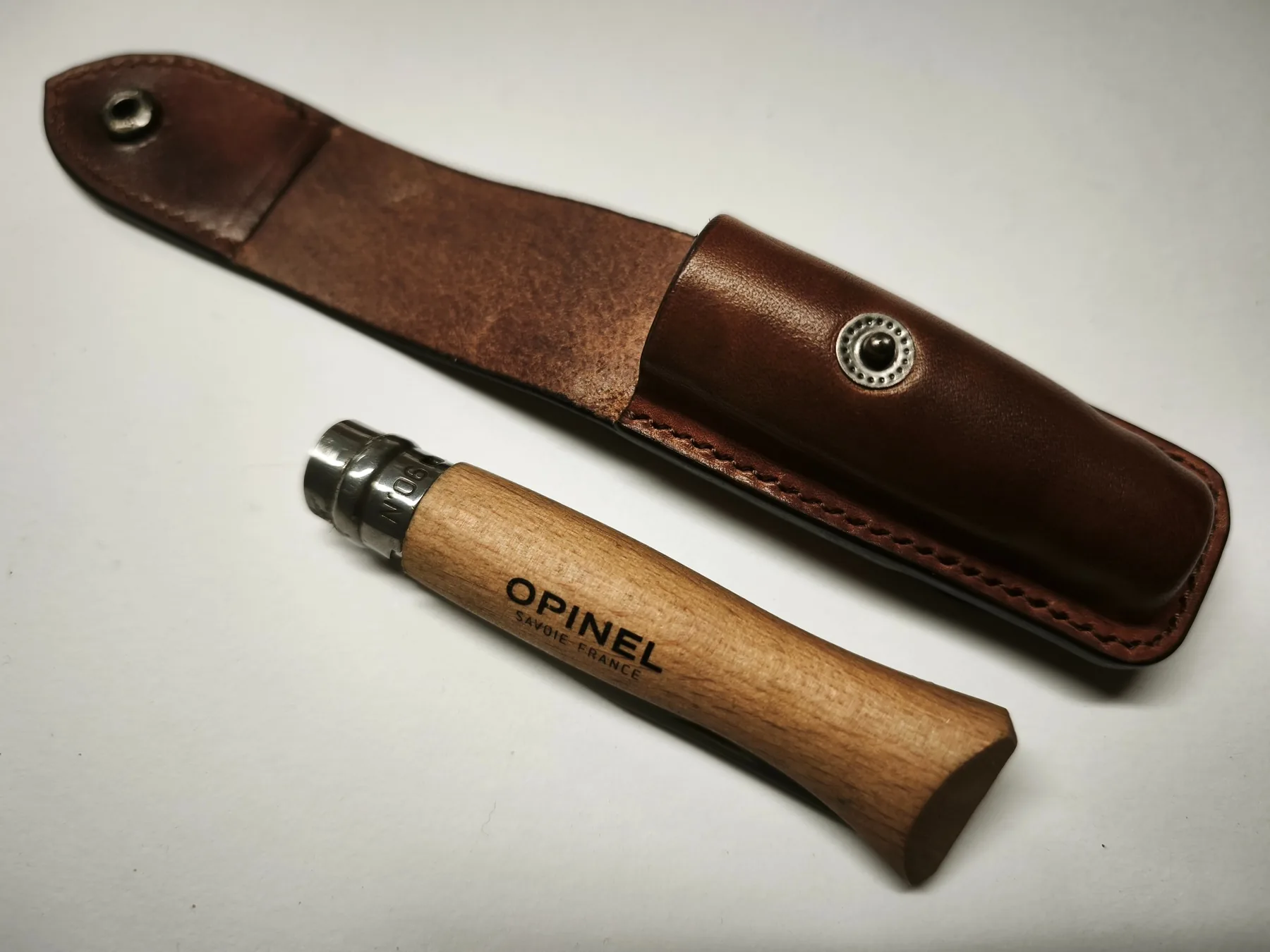 Open fitted leather sheath showing the construction around an Opinel folding knife